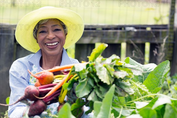 Portrait of senior woman holding carrots and beetroot