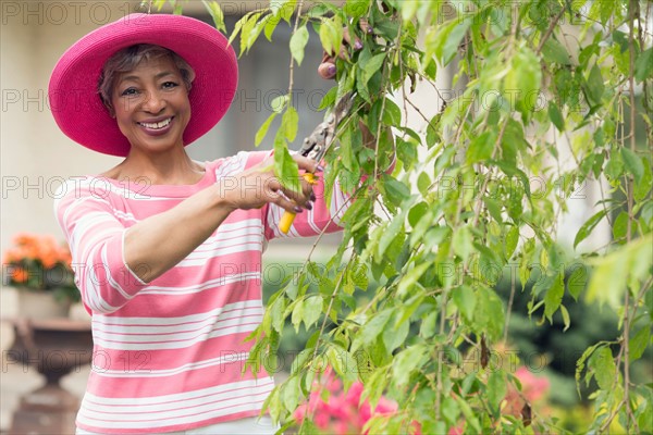 Portrait of senior woman pruning branch