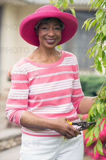 Portrait of senior woman pruning branch