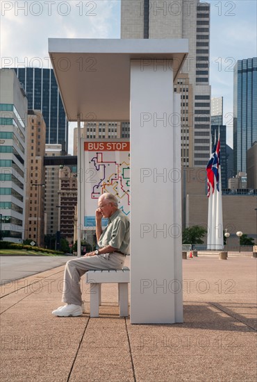 Senior man sitting at bus stop and using mobile phone