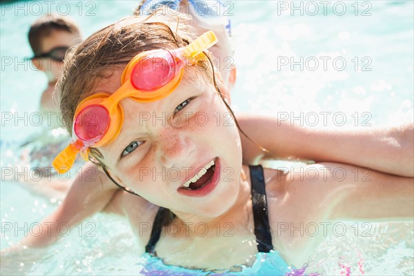 Children (4-5, 8-9) playing in swimming pool