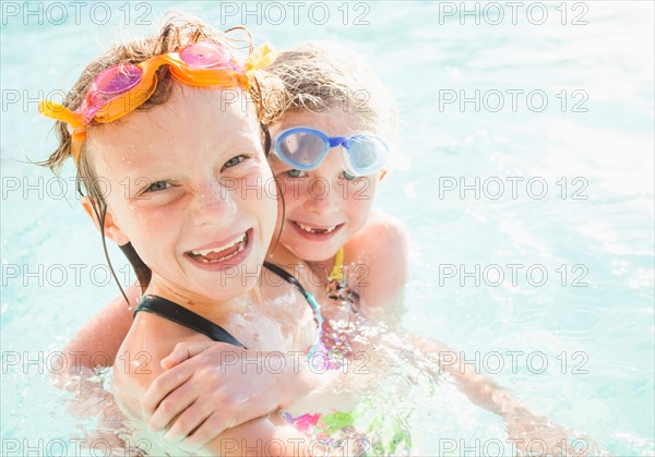 Girlfriends (4-5, 8-9) playing in swimming pool