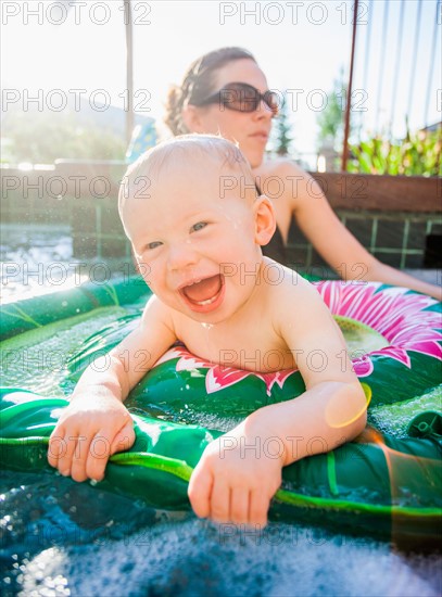 Baby boy (18-23 months) playing in swimming pool with his mother