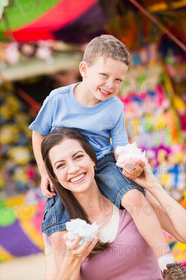 Happy mother with son (4-5) in amusement park eating cotton candy