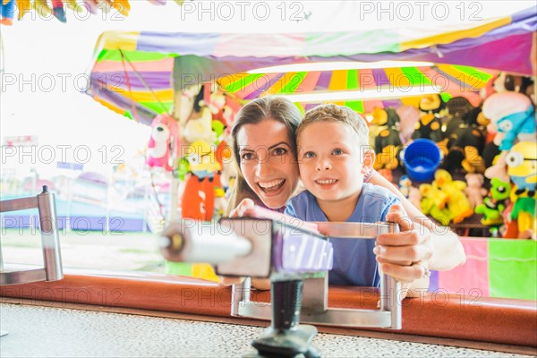 Mother and son (4-5) playing with water gun in amusement park