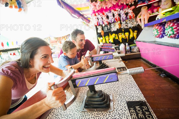 Happy Family with son (4-5) playing with water gun in amusement park