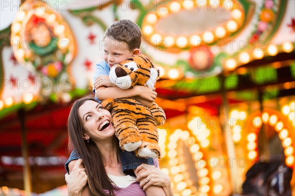 Mother giving her son (4-5) piggyback ride in amusement park