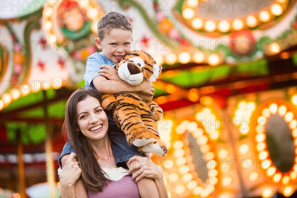 Mother giving her son (4-5) piggyback ride in amusement park