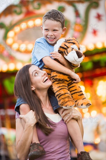 Mother giving her son (4-5) piggyback ride in amusement park