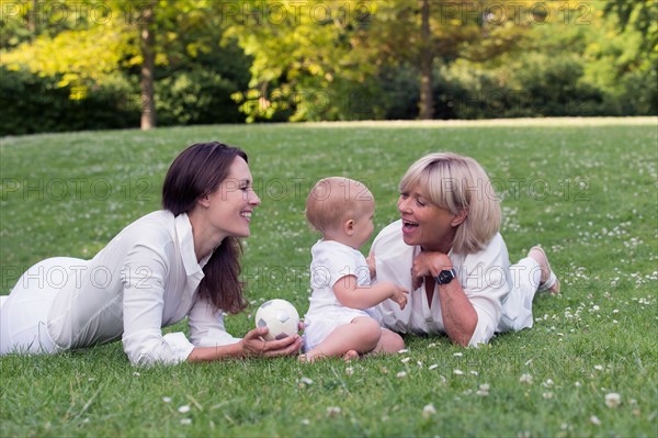 Grandmother with mother and granddaughter (12-17 months) playing on grass