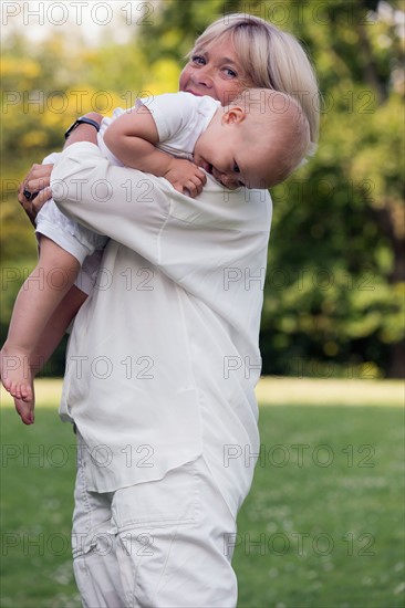 Grandmother carrying her granddaughter (12-17 months) on shoulder