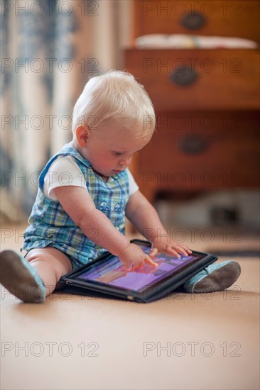 Baby boy (12-17 months) playing with digital tablet