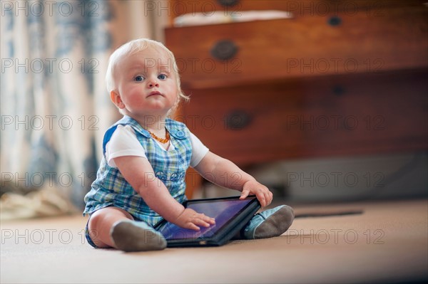 Baby boy (12-17 months) playing with digital tablet