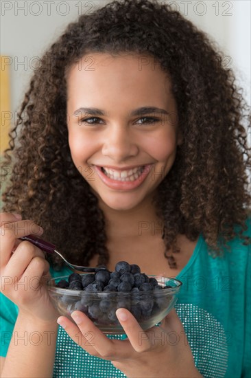 Girl (12-13) holding bowl of black berries