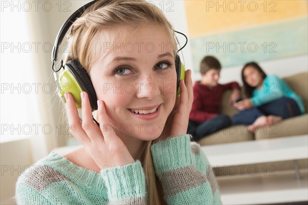 Girl (14-15) listening to music wearing headphones