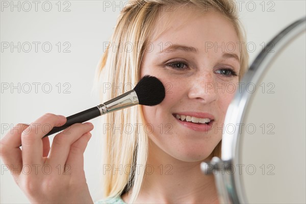 Girl (14-15) applying make up