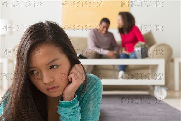 Teenage girl (16-17) crying while two friends (12-13,14-15) whispering behind her