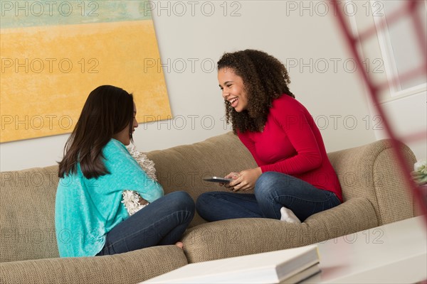 Two friends (12-13,16-17) sitting on sofa