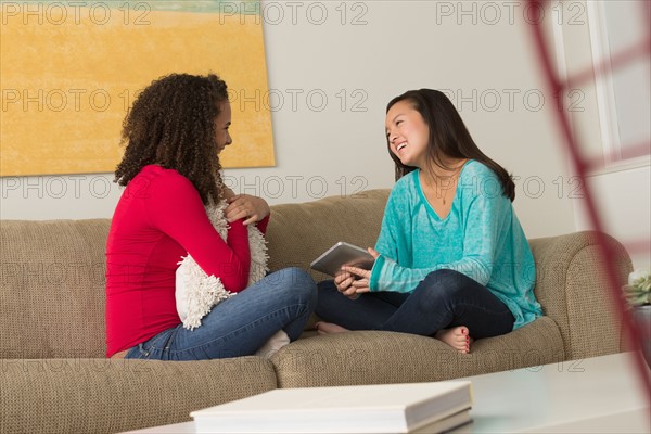 Two friends (12-13,16-17) sitting on sofa
