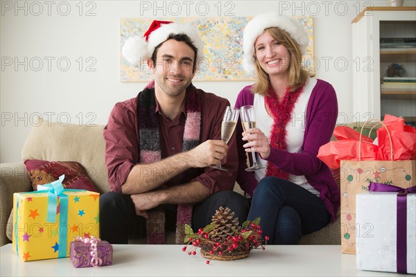 Portrait of young couple wearing santa hats drinking champagne