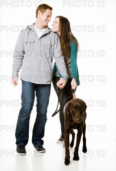 Studio shot of young couple with chocolate labrador