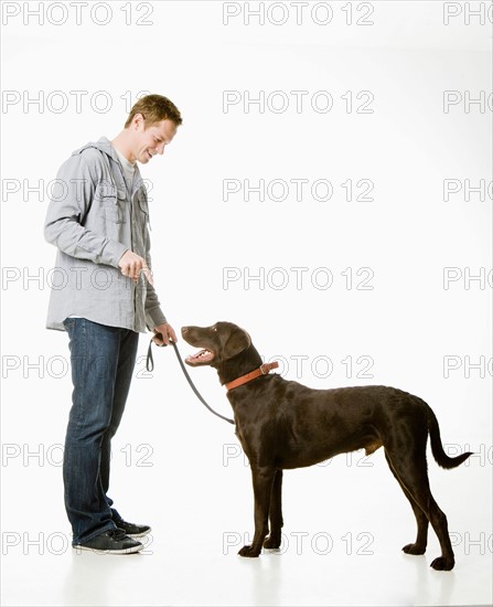 Studio shot of young man with chocolate labrador