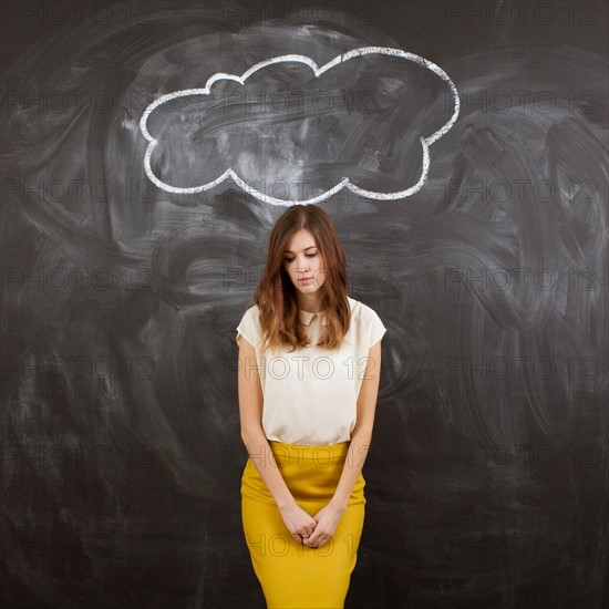 Studio portrait of woman standing under chalk cloud