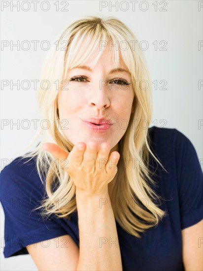 Studio portrait of blonde woman blowing kiss