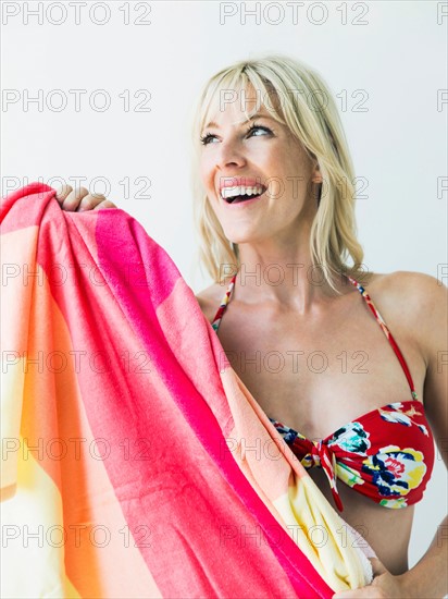 Studio portrait of blonde woman wearing bikini and holding towel