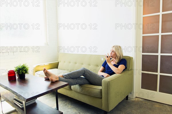 Woman relaxing on sofa and drinking wine