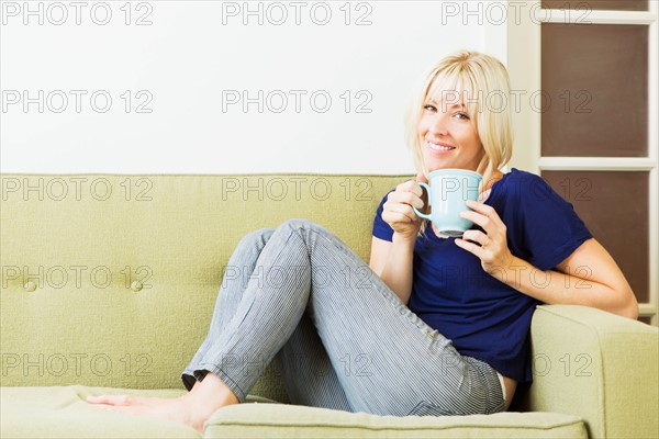 Woman relaxing on sofa and drinking coffee