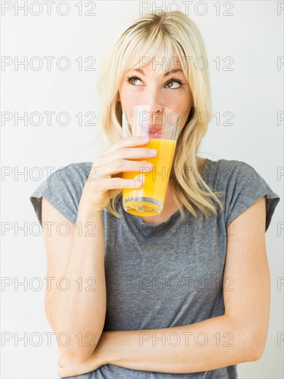 Studio portrait of blonde woman drinking orange juice