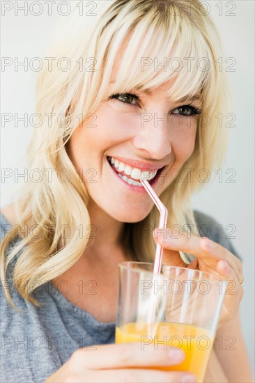 Studio portrait of blonde woman drinking orange juice