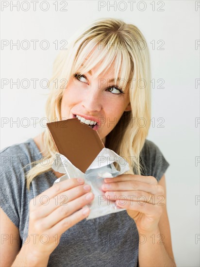 Studio portrait of blonde woman eating chocolate