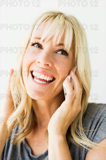 Studio portrait of blonde woman talking on mobile