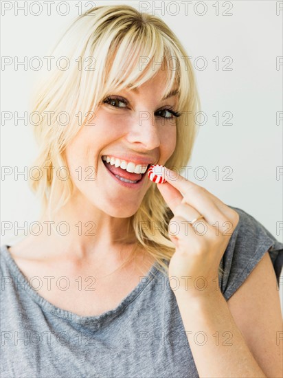 Studio portrait of blonde woman eating candy