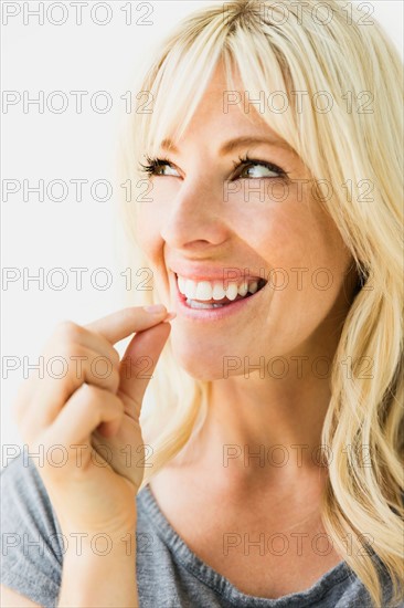 Studio portrait of blonde woman taking pill