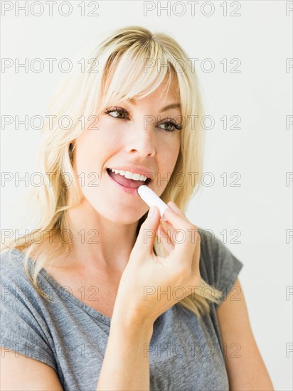 Studio portrait of blonde woman applying lipstick