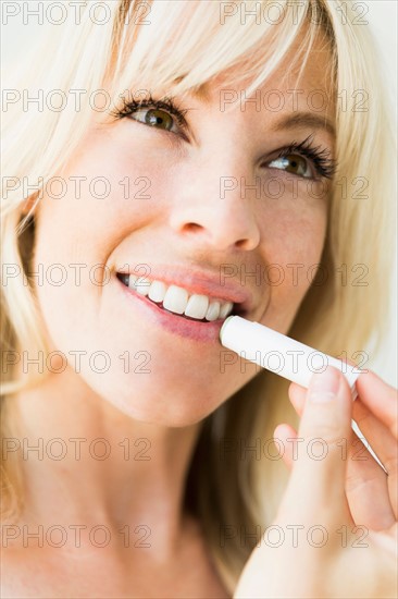 Studio portrait of blonde woman applying lipstick