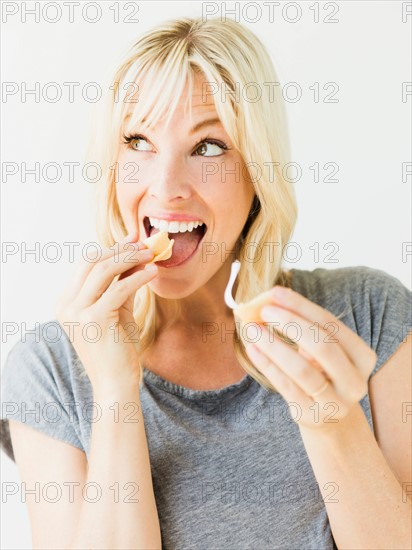 Woman eating fortune cookie, studio shot