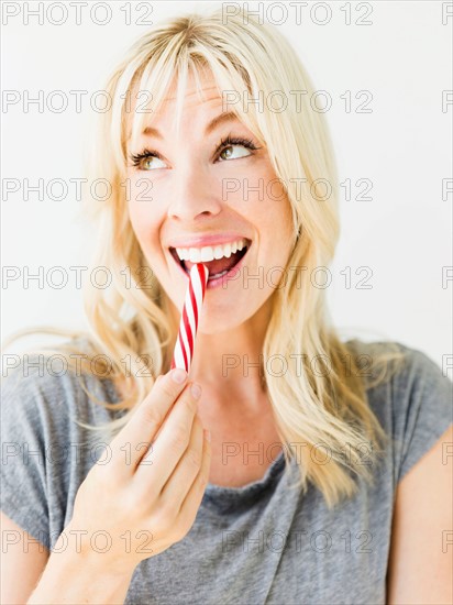 Woman eating candy cane, studio shot