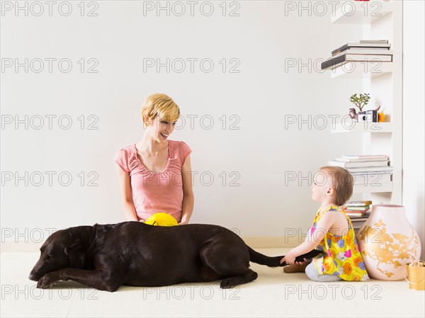 Mother with baby daughter (12-17 months) playing with dog