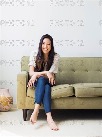 Portrait of happy young woman sitting on sofa