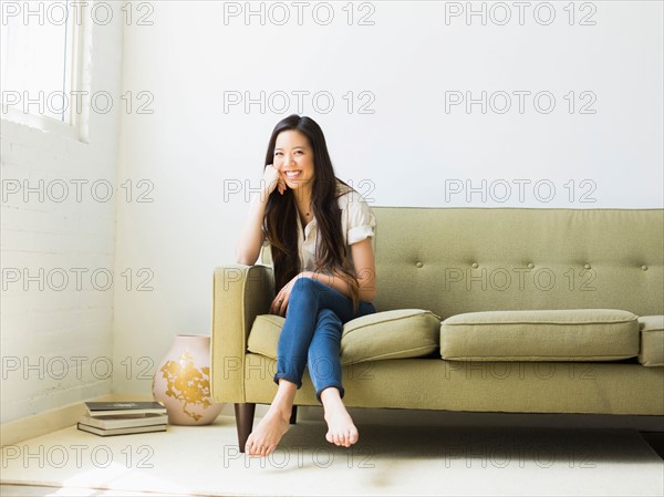 Portrait of happy young woman sitting on sofa