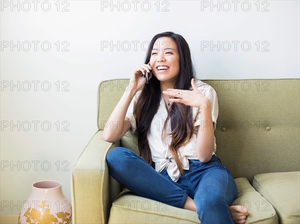 Woman sitting on sofa and talking on phone