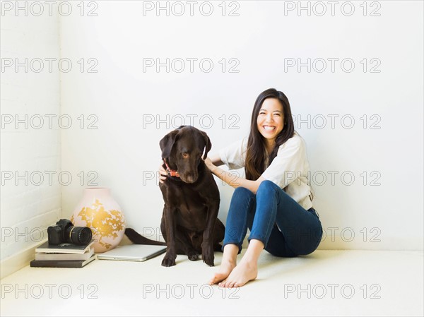 Portrait of woman with dog sitting on floor