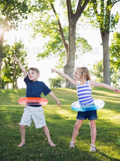 Two kids (4-5, 6-7) playing with inflatable rings in park