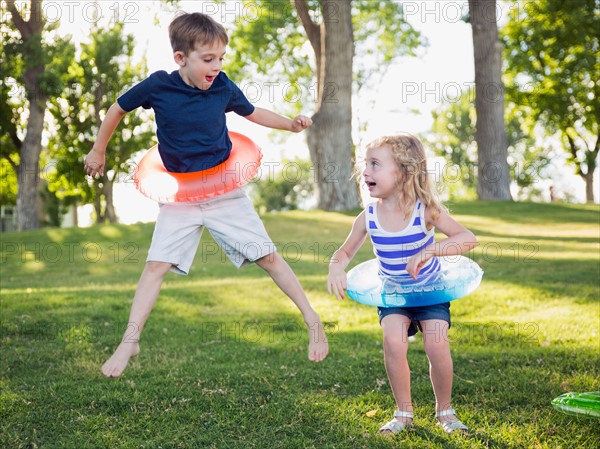 Two kids (4-5, 6-7) playing with inflatable rings in park