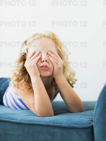 Girl (4-5) lying on bench rubbing her eyes