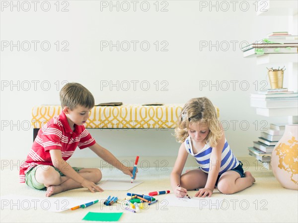 Boy and girl (4-5, 6-7) sitting on floor and drawing